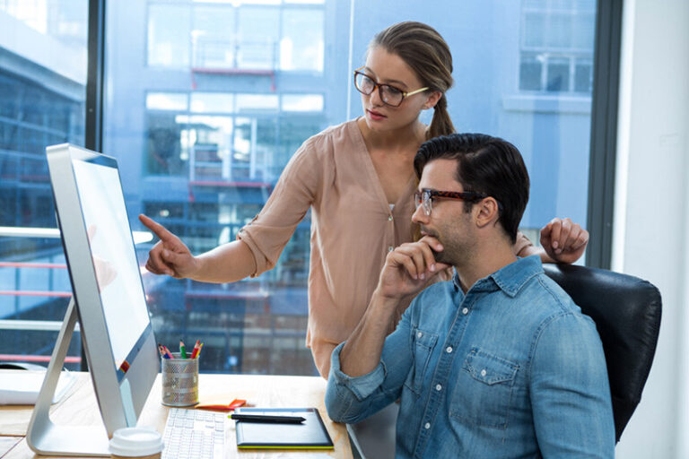 young woman and man analyzing data in front of a computer