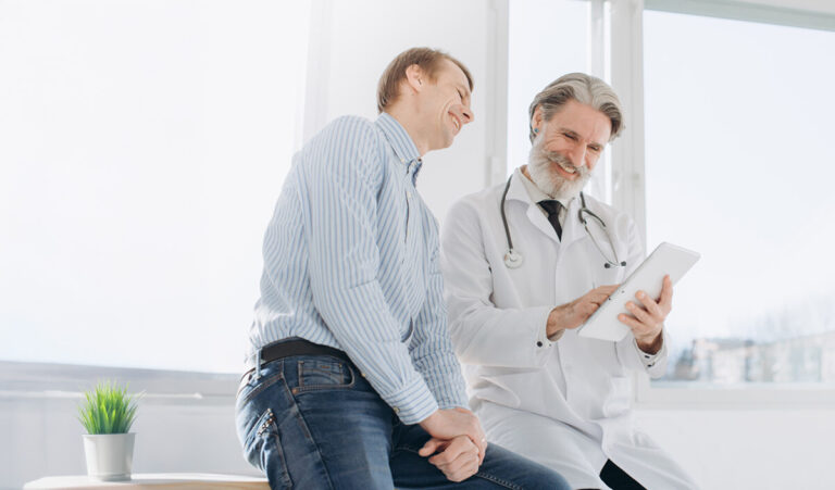 Happy patient with doctor, reading tablet.