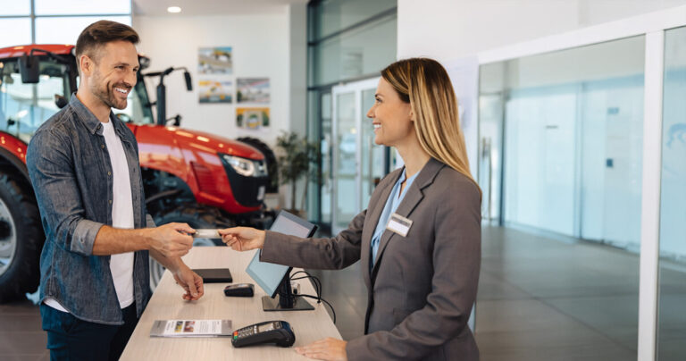 A man paying with a credit card at a tractor's dealership service department