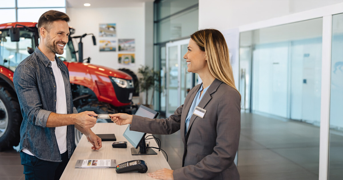 A man paying with a credit card at a tractor's dealership service department